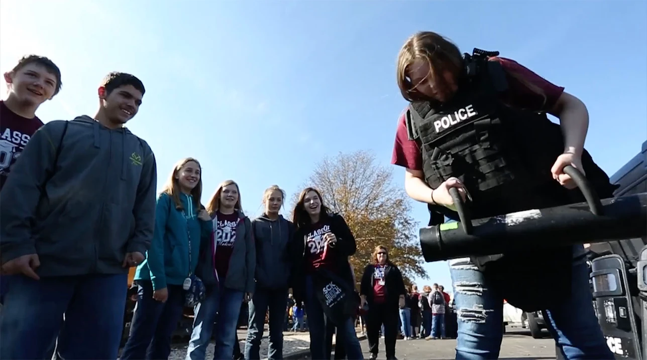Students exploring public safety careers through a hands-on police equipment demonstration