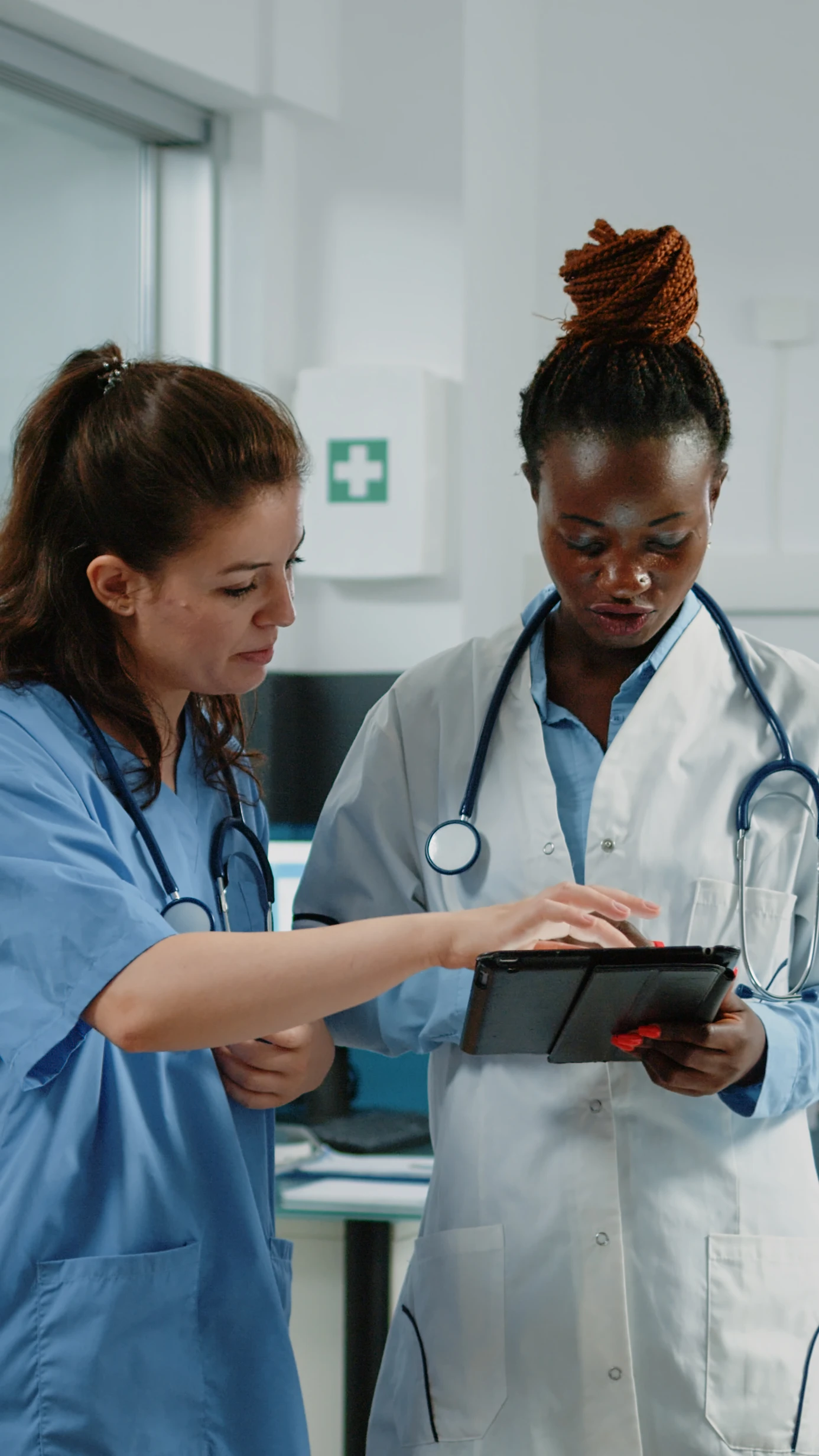 Two healthcare professionals discussing patient care on a tablet