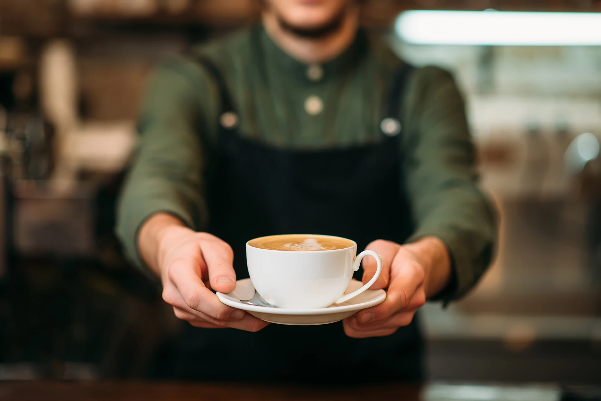 A barista serving a freshly prepared cup of coffee